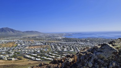 Panorama of the coastal town (Playa Blanca) with sea view and mountains under a clear sky, Playa