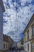 Light bulbs between houses for evening lighting, Cluj-Napoca, Transylvania, Romania