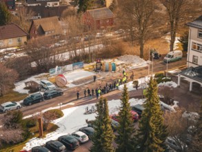Aerial view of a crowd of people next to cable drums on a snowy road, fiberglass groundbreaking,