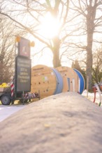 Construction site with cable rolls and a sign in warm sunlight, fiberglass groundbreaking,