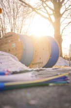 Cable rolls in sunset with snowy ground and bare trees in the background, fiberglass