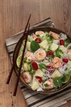 Thai salad with shrimp and rice noodles, pineapple slices, coriander and mint leaves, homemade, no