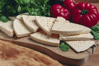 Georgian sliced cheese, on a wooden chopping board, with tomatoes with herbs and lavash, rustic