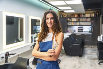 Professional female hairdresser in a modern salon smiling confidently while holding scissors and a