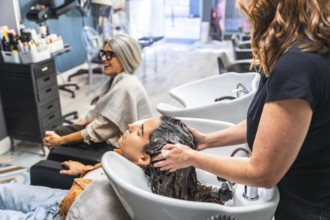 Hairstylist giving a customer a relaxing hair wash and massage at the shampoo station in a modern
