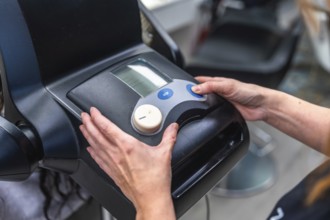 Hairdresser hands adjusting controls on a modern hair treatment machine, delivering professional