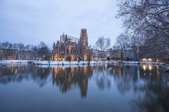 March 18, 2018, winter dusk with snow, illuminated lake and Gothic church Johanneskirche, calm