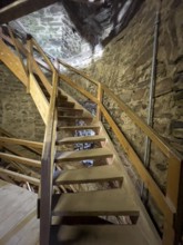 Modern wooden staircase for visitors tourists in keep made of quarry stone masonry Castle tower of