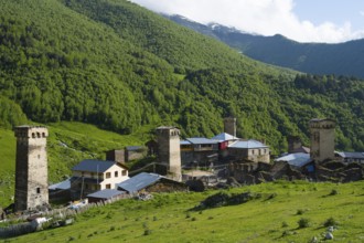 A mountain village with historic towers surrounded by green forests and mountains, defensive