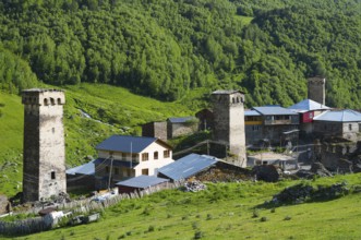 Medieval village with old towers and buildings, nestled in a green hilly landscape, defensive