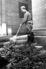 Soldier sweeping boxes of National Socialist medals from a staircase in the Reich Chancellery,