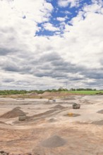 View of an open pit mine with truck and heavy machinery and gravel piles