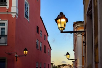 Facades of old houses illuminated by lanterns during sunset on the streets of Pelourinho in