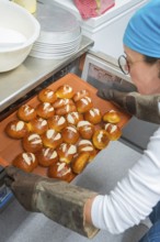 Baker takes freshly baked rolls out of the oven on a baking tray, bake rolls, Haselstaller Hof,