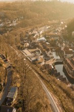 Aerial view of a village with tracks and river surrounded by trees in sunlight, test run on the new