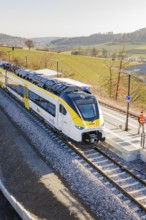 Modern train on the platform in a landscape surrounded by fields under clear skies, test run on the