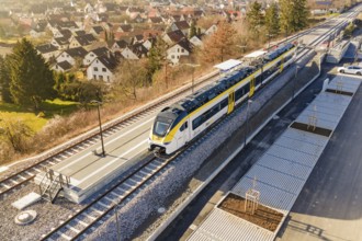 Train at a small train station surrounded by village houses and green countryside, test trip on the