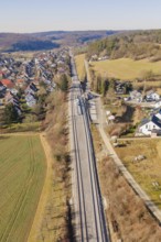 Aerial view of railroad tracks running through a rural area with houses and fields, test run on the