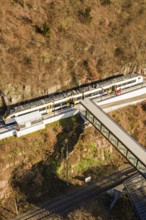 A train below a footbridge, along an autumnal climb, test run on the new Hermann-Hesse railway with