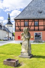 Sandstone figure bear with coat of arms on Bärenstein market square, church in the background,