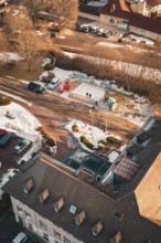 Bird's eye view of a snowy road with buildings and parked cars on a sunny winter day, Freudenstadt,