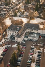 A large building with an adjacent parking lot and a few snow-covered cars, district office,