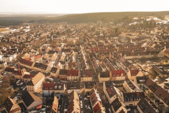 Aerial view of a winter town with rustic houses and snow-covered streets in warm lighting,