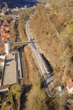 Aerial view of a railway line along a wooded slope with urban surroundings, test run on the new