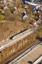 View of house and vegetation with train traveling through hilly urban landscape, test run on the