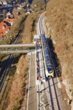Train on platform in hilly landscape, with bridge and urban background, test run on the new