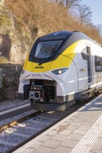 Yellow-black train at a small train station in a mountainous landscape, test run on the new