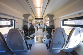 Modern train interior with grey seats and bright daylight through the windows, test run on the new