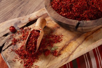 Spice saffron threads, in a wooden bowl, on a wooden table, top view, close-up