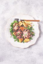 Grilled octopus with baked potatoes and fresh herbs, on a decorative light plate, homemade, no
