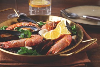 Seafood and black rice paella, in a frying pan, homemade, on a wooden table, no people