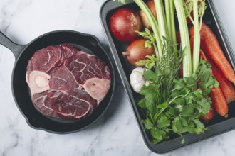 Sknuckle on the bone, raw meat for ossobuco, in a cast-iron pan, baking sheet with vegetables, top