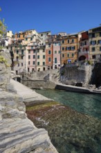 Colourful houses along a rocky coast with clear sea water under blue sky, fishing village of