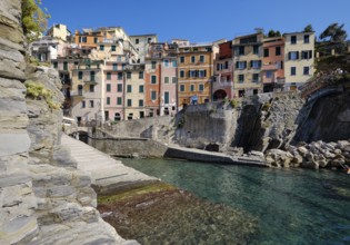 Colourful houses along a rocky coast with clear sea water under blue sky, fishing village of