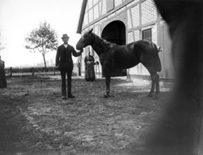 Man with horse posing for the photo, woman, farm, ca. 1920-1930, retro, vintage, old, historic,