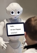 Pepper, a humanoid robot with a tablet and a boy in dialogue, artificial intelligence, AI, Germany