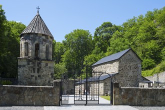 Stone church in a forest under a blue sky with an entrance gate, Chitakhevi Church of St. George,