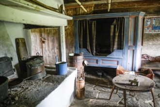 Rustic old kitchen with antique stove and blue-painted wooden furniture. The soil is made of stone