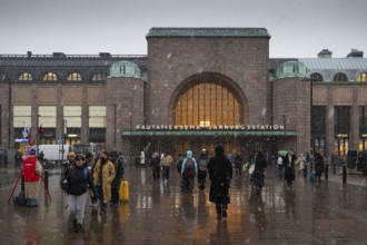 Busy side entrance to Central Station with Christmas decoration during snowfall, Helsinki, Finland