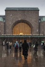Busy side entrance to Central Station with Christmas decoration during snowfall, Helsinki, Finland