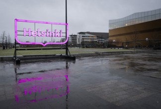 Large pink glowing Helsinki city logo, in front of Oodi Central Library and Cultural Center,