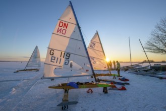 Ice sailboats in evening light and bright sun on the shore of a frozen lake Dümmer, Dümmer See,