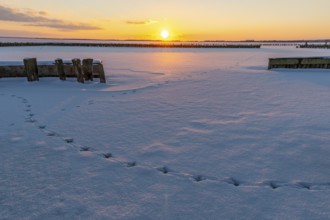Snow-covered landscape at sunset with footprints in snow and calm atmosphere, snow-covered area of