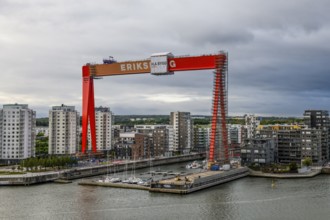Large orange construction crane in front of modern residential buildings on the site of the former