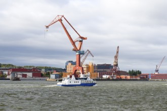 Large industrial port crane and ship on water under cloudy sky in Gothenburg harbour, Gothenburg,