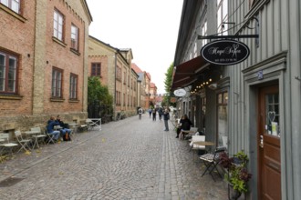 Lively street scene with cafés and historic buildings along a cobblestone street in Gothenburg's